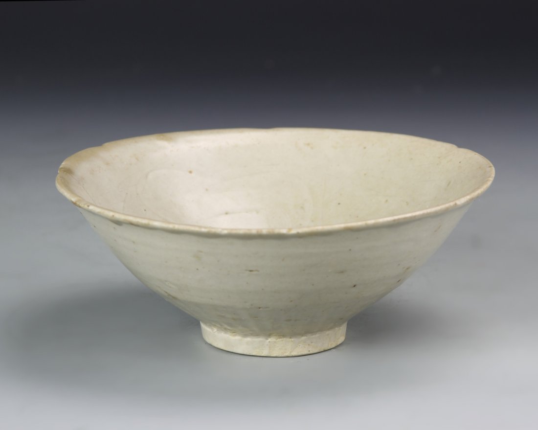 Chinese Yaozhou Celadon Bowl: The deep bowl rising to a notched foliate rim, the interior incised with floral sprigs, covered overall with thick layer of pale celadon glaze, except the foot pad. Provenance: Estate of Gustav Ficshe