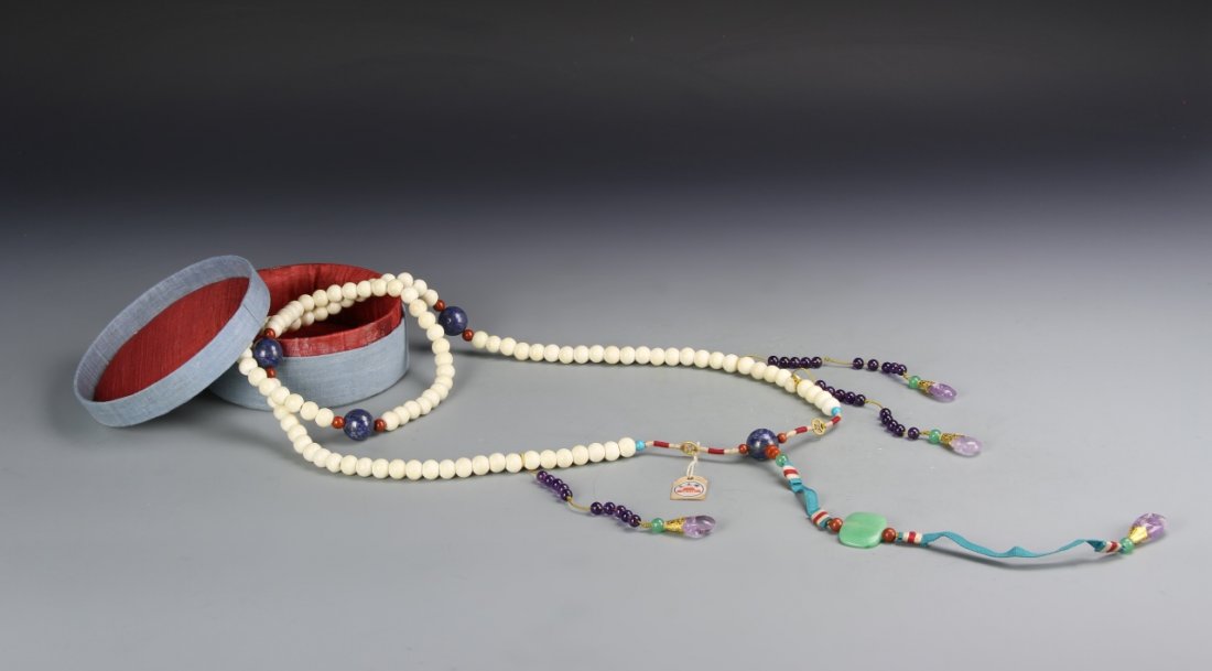 Chinese Deer Antler Court Necklace: Comprising 108 spherical beads carved from deer antler spaced by four larger lapis beads and attached with three strands of amethyst beads, and a jadeite beiyun plaque, each suspending a amethyst tear