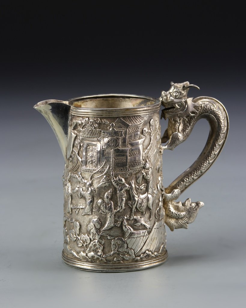 Chinese Silver Creamer: China, 19th C., silver creamer, scenes around body of figures and horses outside of buildings, handle in form of dragon attached to cup at the feet, marks. Height 3 1/4 in.