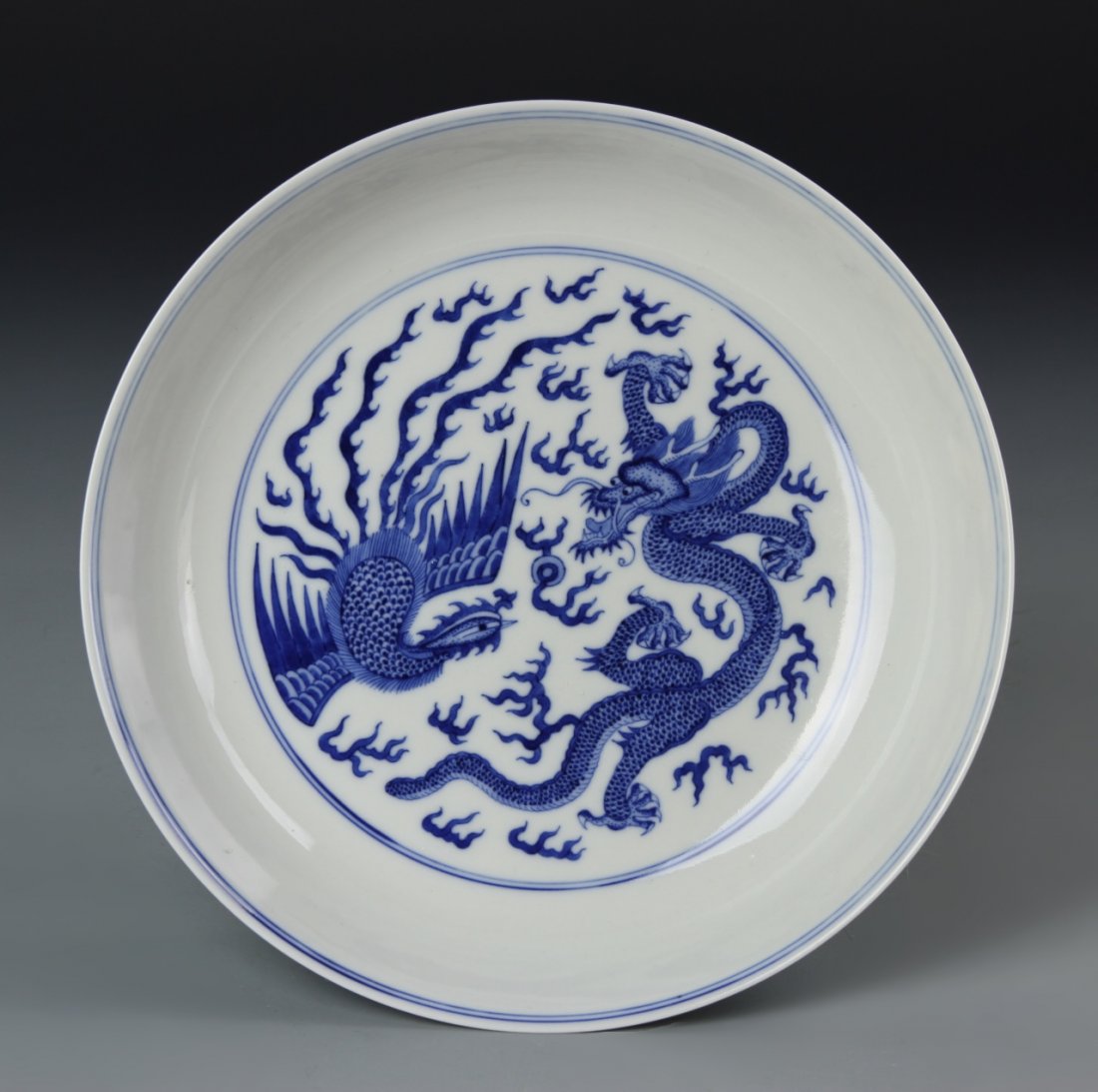 Chinese Blue and White Dragon and Phoenix Plate: China, blue and white dragon and phoenix plate, on a slightly raised base, with a white ground decorated in a blue glazed pattern of dragons and phoenixes amongst flames, with a double ring mark on th