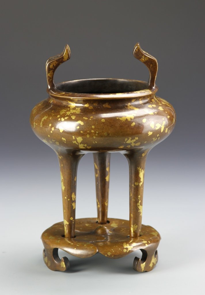 Chinese Bronze Tripod Censer: China, 19th C., bronze tripod censer with two raised handles, decorated with gilt flakes, three legs which stand within a circular base which is stamped with a mark. Height 6 3/4 in., Width 4 1/2 in.