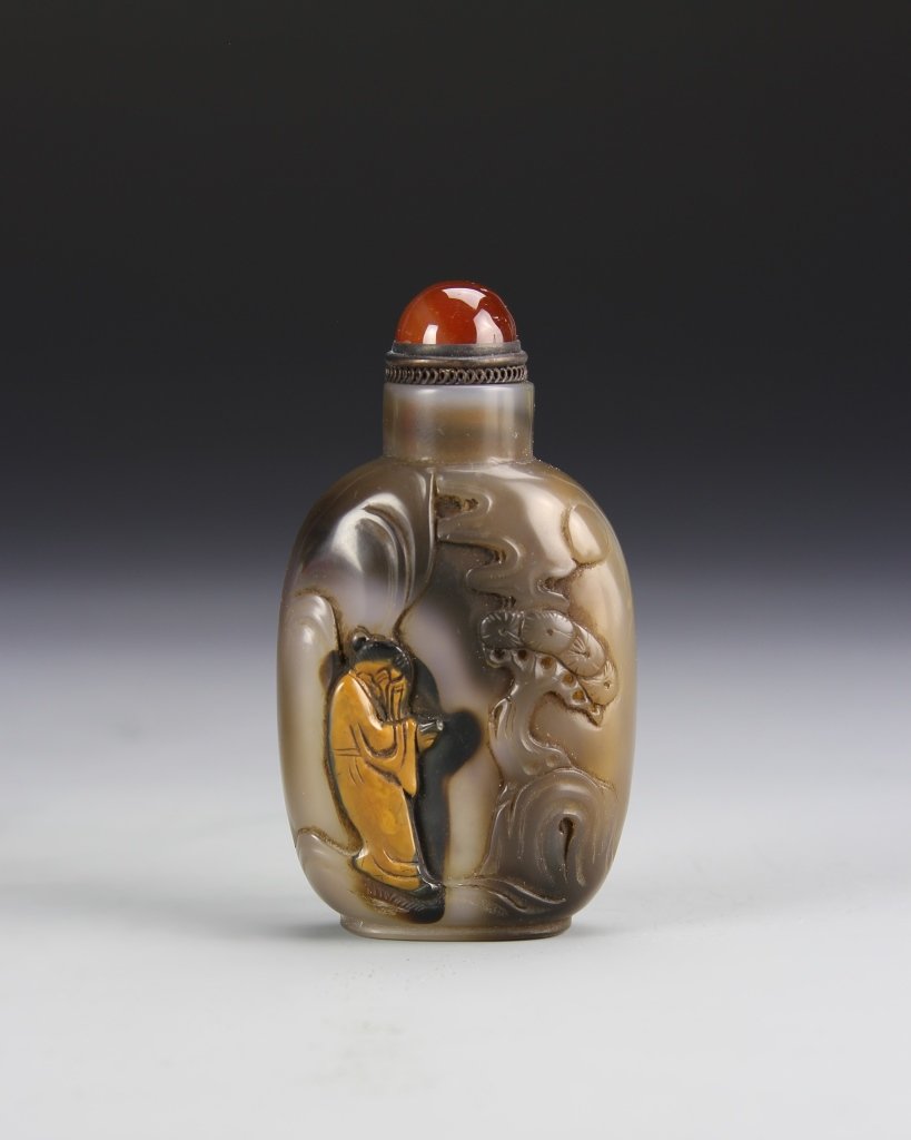 Chinese Agate Snuff Bottle: China, 19th C., agate snuff bottle, in a dark brown hue with lighter variations, carved on one side with a figure in a landscape. Height 2 7/8 in.