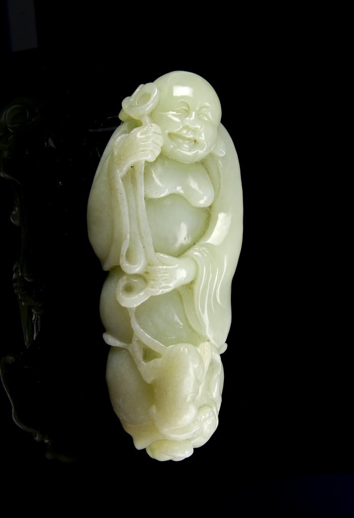 Chinese Jade Buddha: China, 19th C., jade Buddha, carved with a laughing face and open robe to reveal a round belly, holding a staff, with a frog resting on his lower body, in a pale green hue. Height 5 in.