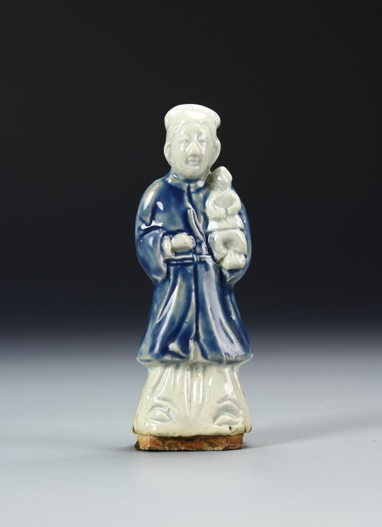 Chinese Guanyin Statue: China, Ming period, Guanyin statue, simplistic carving of a man standing wearing blue robes and holding a small baby, rust brown coloring on the underside of the base. Height 3 3/4 in. Provenance: Pri
