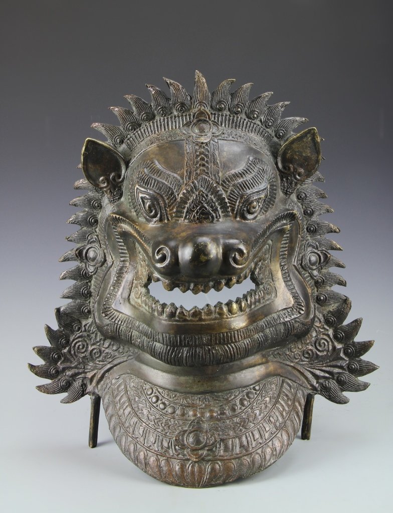 Tibetan Bronze Mask: Tibet, 19th C., bronze mask, detailed carving highlighting an aggressive creatures face, with wide open mouth and sharp teeth, free standing on two legs. Length 16 3/4 in.