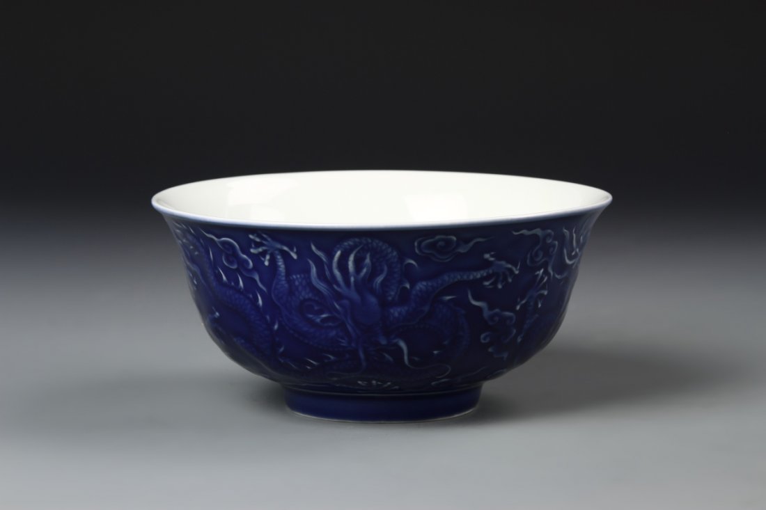 Rare Chinese Blue Enameled "Dragon" Bowl: The deep rounded sides rising to a flared rim, the exterior molded with three five-clawed writhing dragons amid suyi-shaped clouds, all in rich blue enamel, base with six-character Yungcheng mark, 6.1