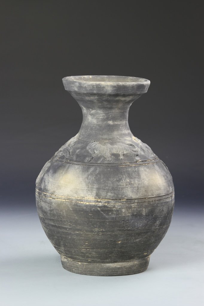 Chinese Pottery Jar: China, Han Dynasty, pottery jar, on a slightly raised base, in a round form, with a long, slender neck and wide, flouted rim, in a black hue, with incised images of tigers at the shoulders and several