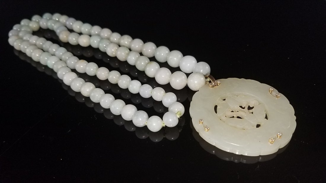 Hetian Jade Pendant: China, ROC., Hetian jade, round pendant with floral edging and pierced decoration with six small diamond stones, attached to a long strand of white, identicle shaped beads. Pendant Diameter 2 1/4 in.