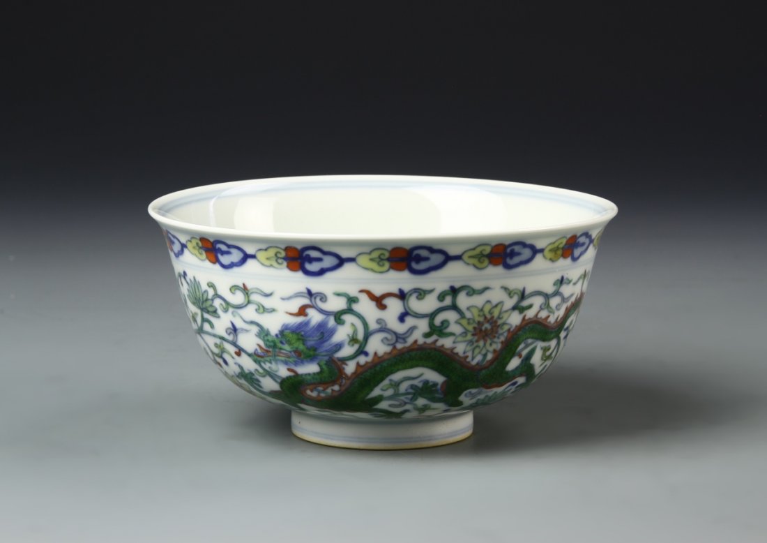 Chinese Doucai Bowl: China, 19th C., Doucai bowl, flared rim at mouth, undulating sides to footed base, colorful dragon between borders against white ground, Kangxi mark. Width 5 7/8 in., Height 2 3/4 in.