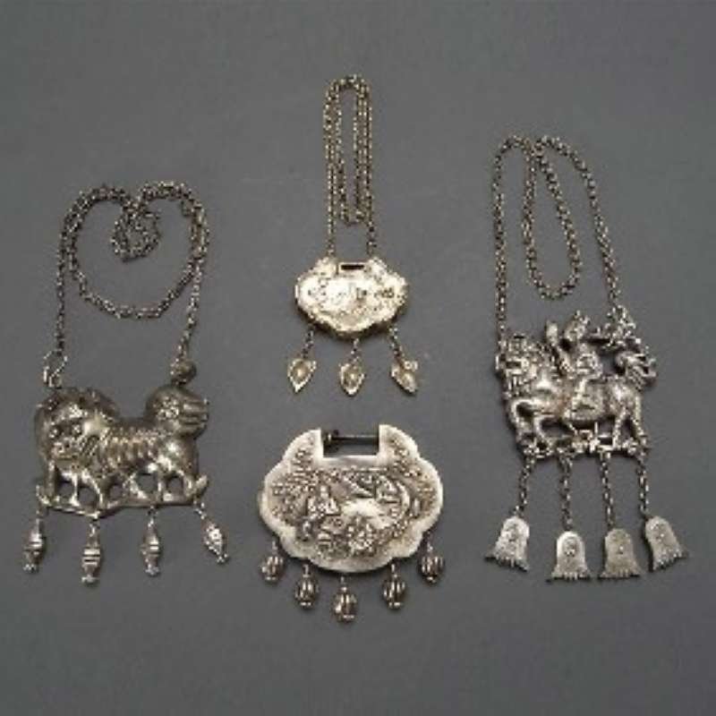 A Group of Four Mandarin Silver Locks and Necklace: A Group of Four Mandarin Silver longevity Locks and Necklaces, each with hanging decorations depicting figures, characters and mythical beasts 四样银质长命锁 