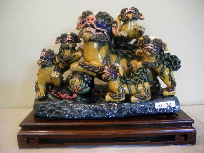 Ornate Chinese Porcelain Lion & Cubs Figure & Wood: A signed & ornately detailed Chinese earthenware enameled lion with cubs figure resting atop a fine wood base, measuring 13" across x 9 ½" high x 7" deep.