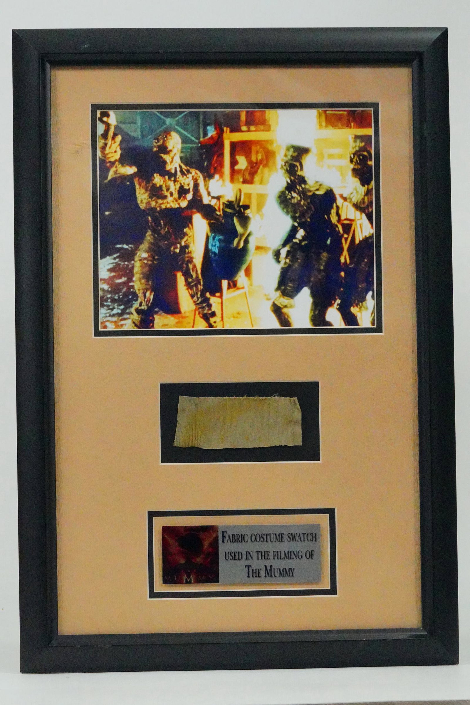 The Mummy (1999) Costume Fabric Swatch W/COA: The Mummy (1999) Costume Fabric Swatch in Exhibit Quality Framed Display W/COA - This exhibit quality framed display contains a costume fabric swatch used in the filming of the Stephen Sommers 1999 fa