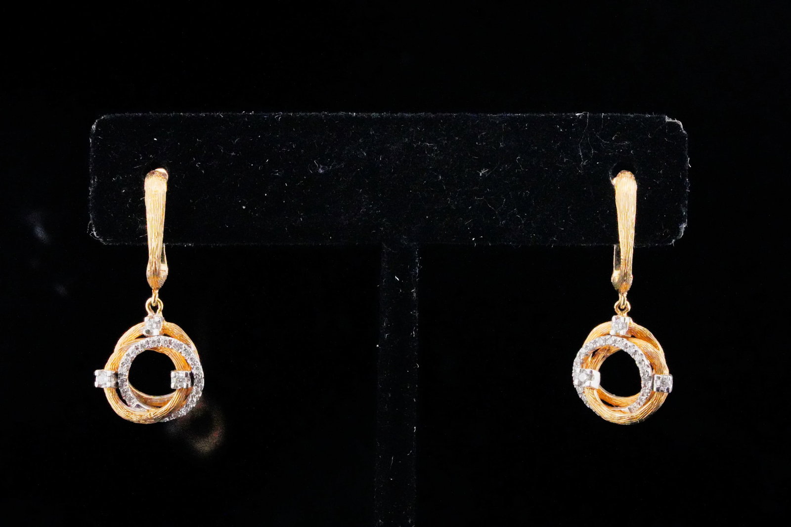 14K Yellow/White Gold and 0.20ctw Diamond Earrings: 14K Yellow/White Gold and 0.20ctw Diamond 1.10" Drop Earrings - These elegant drop earrings are crafted of 14k yellow gold and feature a swirled design with a white gold accent, lined with approximate