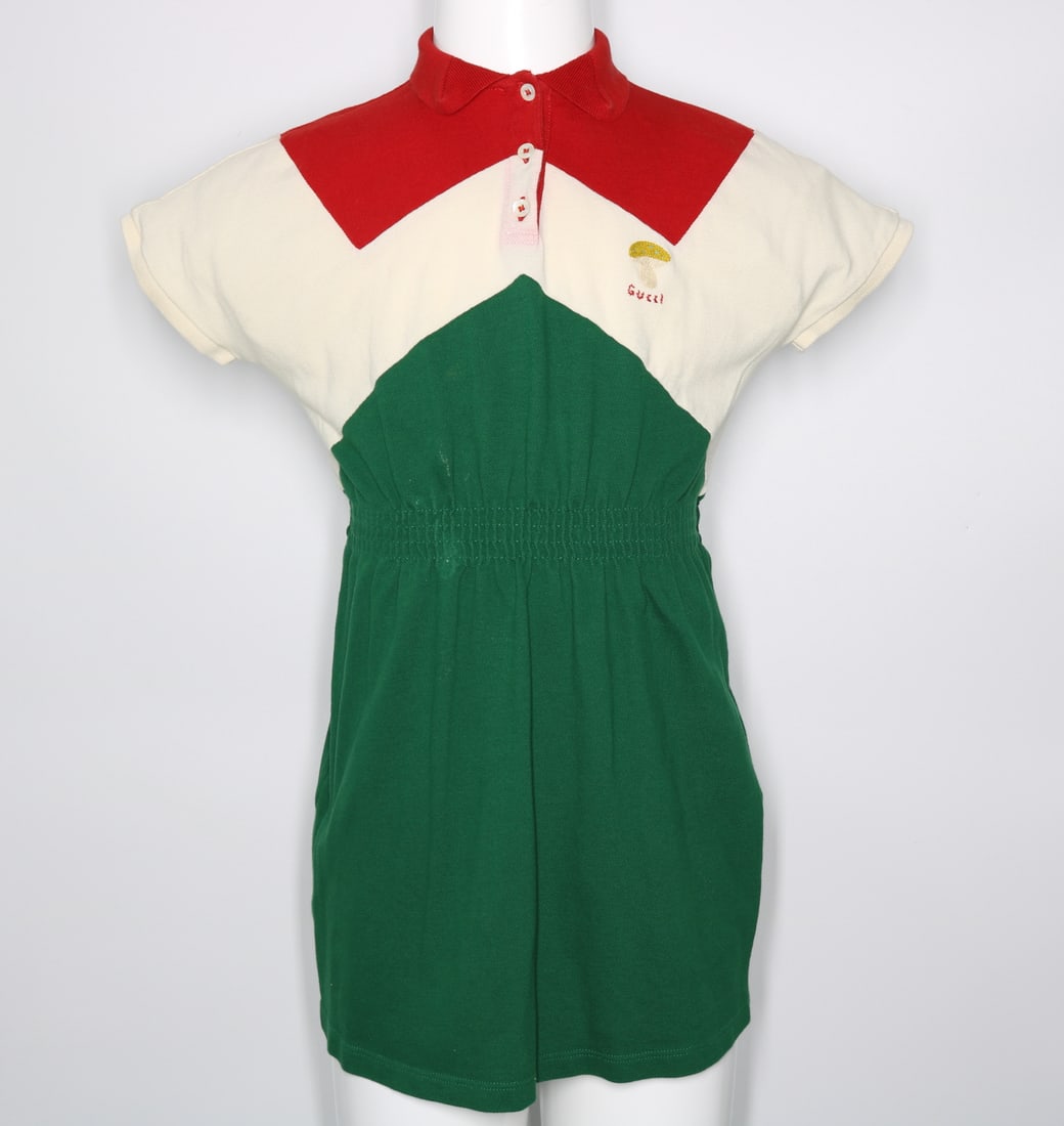 Gucci Children's Dress with Details: GUARANTEED AUTHENTIC. Gucci Children's Dress with Details - This charming Gucci children's dress is a delightful blend of style and whimsy. The dress is rendered in a vibrant green, featuring an intri