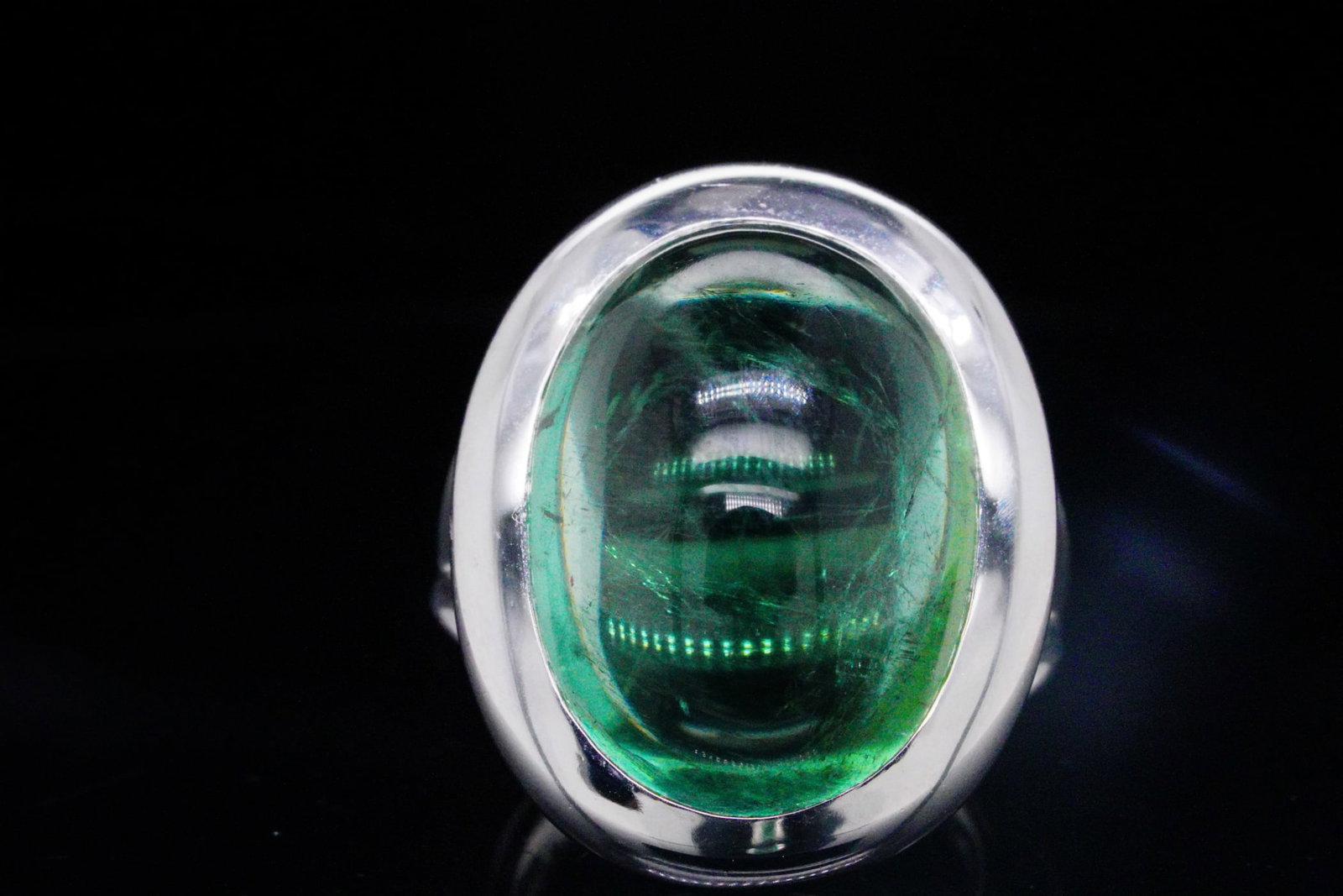 Bucherer 25.70ct Green Tourmaline and 18K Ring: Bucherer 25.70ct Cabochon Green Tourmaline and 18K White Gold Ring - This striking Bucherer ring showcases a magnificent 25.70ct cabochon green tourmaline, a gemstone prized for its lush, vibrant hue