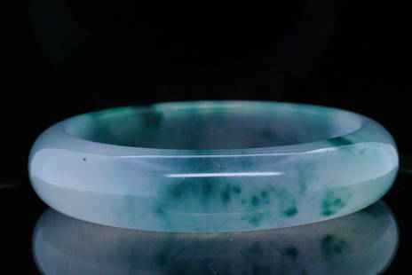 Elegant Jadeite Bangle Bracelet: Elegant Jadeite Bangle Bracelet - A beautiful jadeite bangle bracelet, expertly carved from a single piece of translucent stone with rich green inclusions. This rounded bangle showcases a harmonious b