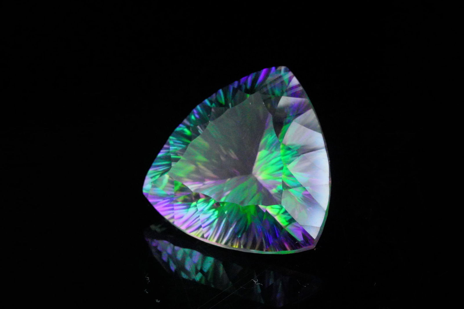 38.85ct Trillion Cut Mystic Topaz: 38.85ct Trillion Cut Mystic Topaz - A dazzling and oversized mystic topaz weighing approximately 38.85 carats. This trillion cut gemstone exhibits vibrant iridescent hues, flashes of purple, green, an