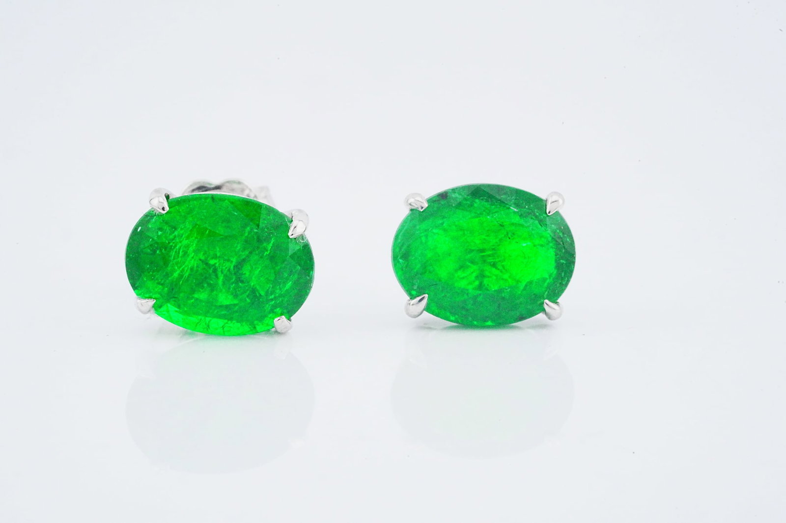 4.60ctw Zambian Emerald and 18K White Gold Earrings: 4.60ctw Zambian Emerald and 18K White Gold Stud Earrings - This item will come with a $15,000 insurance valuation report in the winning bidder's name by a graduate appraiser. A refined pair of emerald