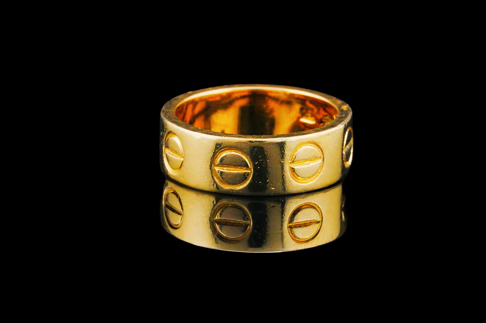 Solid 18K Yellow Gold Ring: Solid 18K Yellow Gold Ring - Beautifully crafted in rich 18K yellow gold, this sleek bangle features a classic, minimalist design accented with repeating screw-head style motifs around the exterior. T