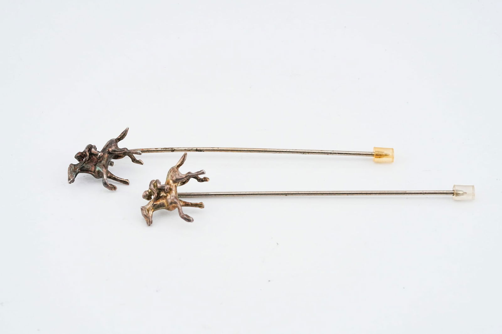 Lot of (2) Sterling Silver Topped Equestrian Stick Pins: Lot of (2) Vintage Sterling Silver Topped Equestrian Stick Pins - A finely detailed pair of vintage stick pins with sterling silver jockey on horse motifs set on metal pins. The figures are sculpted w