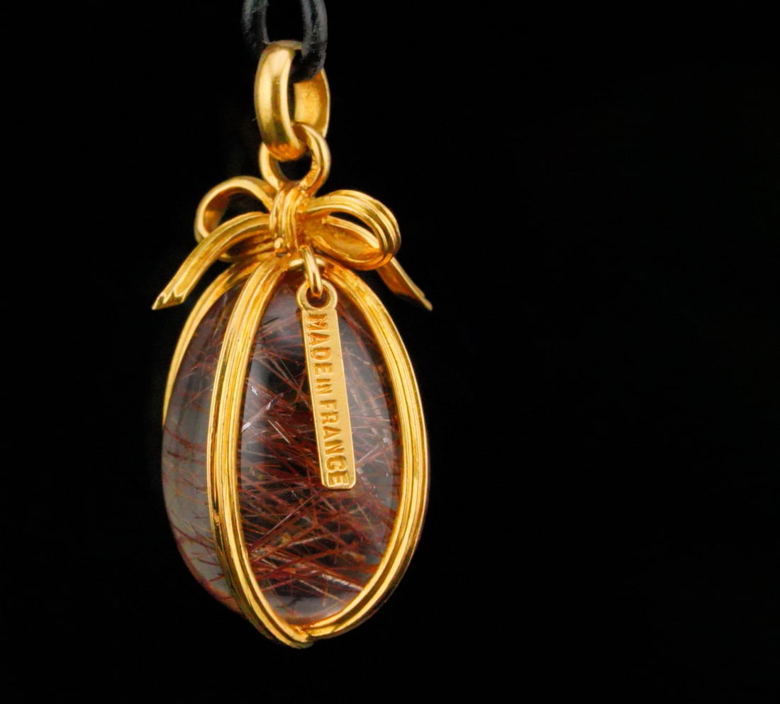French Rutilated Quartz and 18K Egg Pendant: French Rutilated Quartz and 18K Yellow Gold Egg Pendant - A beautifully crafted French pendant featuring an oval rutilated quartz wrapped in an elegant 18k yellow gold wirework setting. The quartz dis