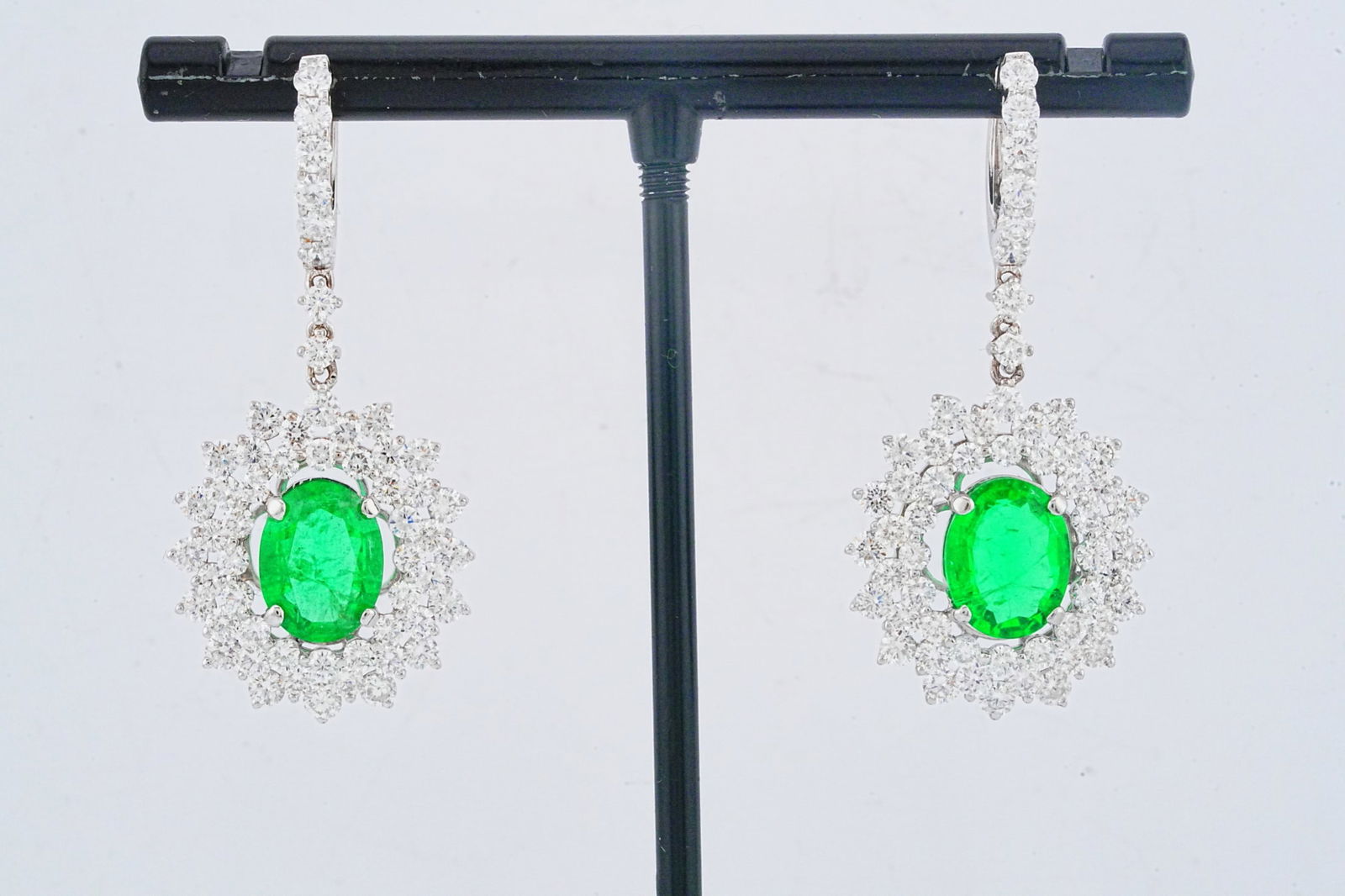 3.90ctw Diamond, 3.20ctw Emerald and 18K Earrings: 3.90ctw VS1-SI1/G-H Diamond, 3.20ctw Emerald and 18K White Gold 1.5" Drop Earrings - This item will come with a $20,500 insurance valuation report in the winning bidder's name by a graduate appraiser.