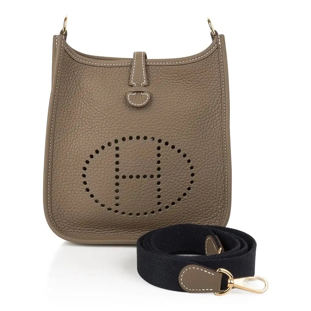 Hermes Etoupe Clemence Leather Mini Evelyne TPM: Hermes Etoupe Clemence Leather Mini Evelyne TPM W/Navy Strap and Gold Hardware (Includes Box and Sleeper) - The Hermes Evelyne TPM in Etoupe Clemence leather offers a perfect balance of casual sophist