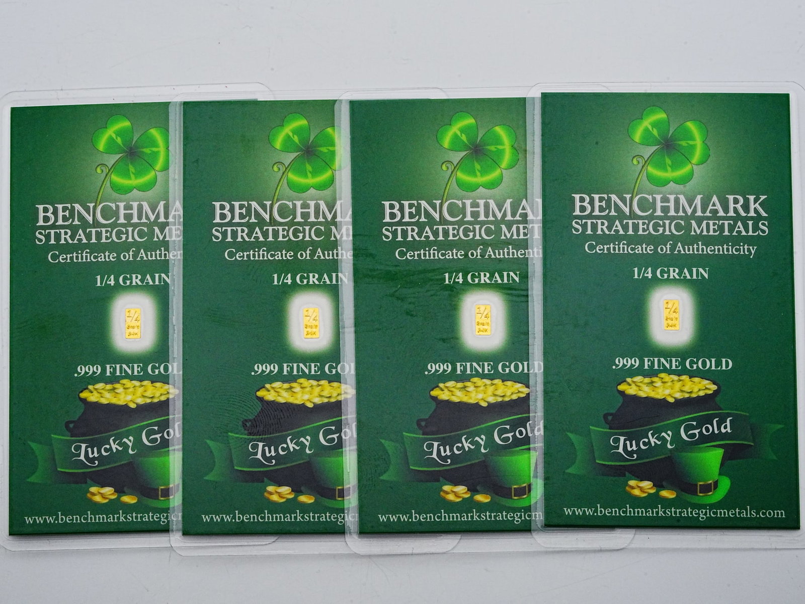Lot of (4) 1/4 Grain .999 Fine Gold "Lucky Gold" Bars: Lot of (4) Benchmark Strategic Metals 1/4 Grain .999 Fine Gold "Lucky Gold" Bars in Sealed Certificates - A collectible and novelty fractional gold lot featuring four Benchmark Strategic Metals