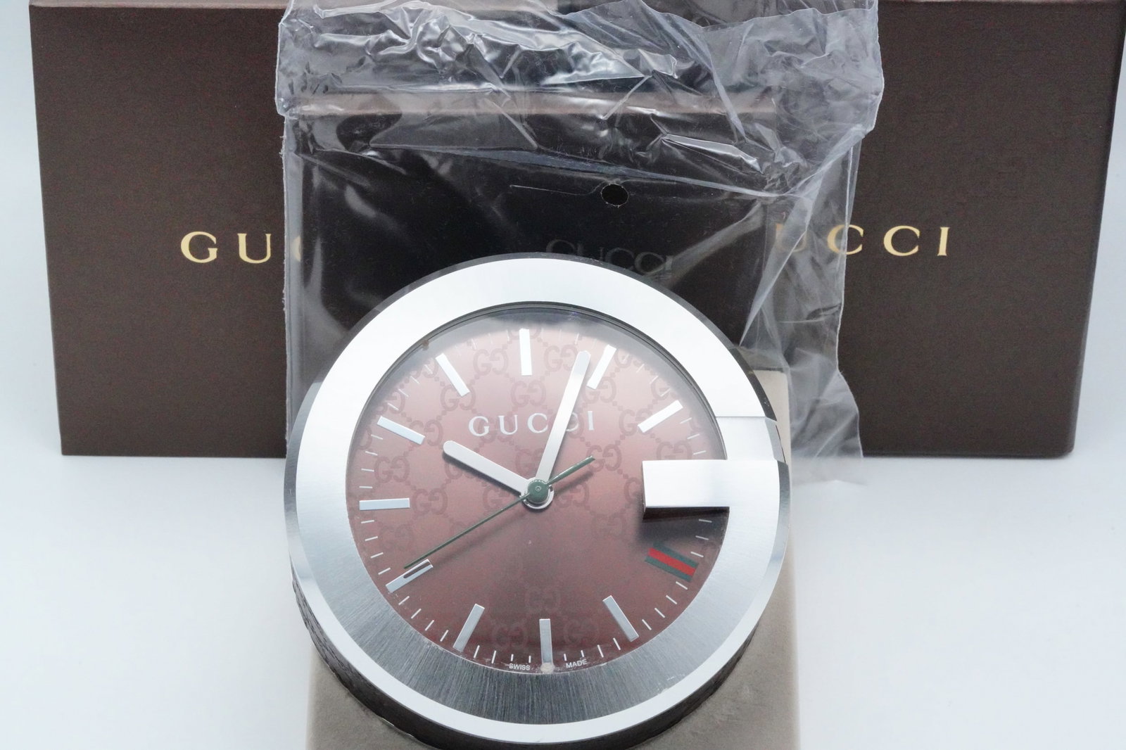 Gucci Brown GG Pattern Dial Table Clock W/Box: Gucci Brown GG Pattern Dial Table Clock W/Box, Tag and Booklet - This table clock from Gucci features a stainless steel and leather case. fixed G-shaped bezel, brown GG pattern dial with silver-tone h