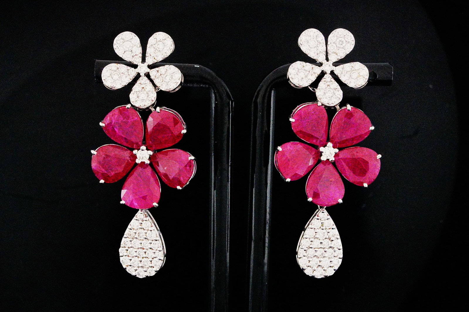 27.65ctw Ruby, 3.30ctw Diamond and 18K 2.10" Earrings: 27.65ctw Ruby, 3.30ctw VS1-VS2/G-H Diamond and 18K White Gold 2.10" Floral Drop Earrings - THIS ITEM WILL COME WITH A $27,500 INSURANCE VALUATION REPORT. These vibrant floral drop earrings showcase ap