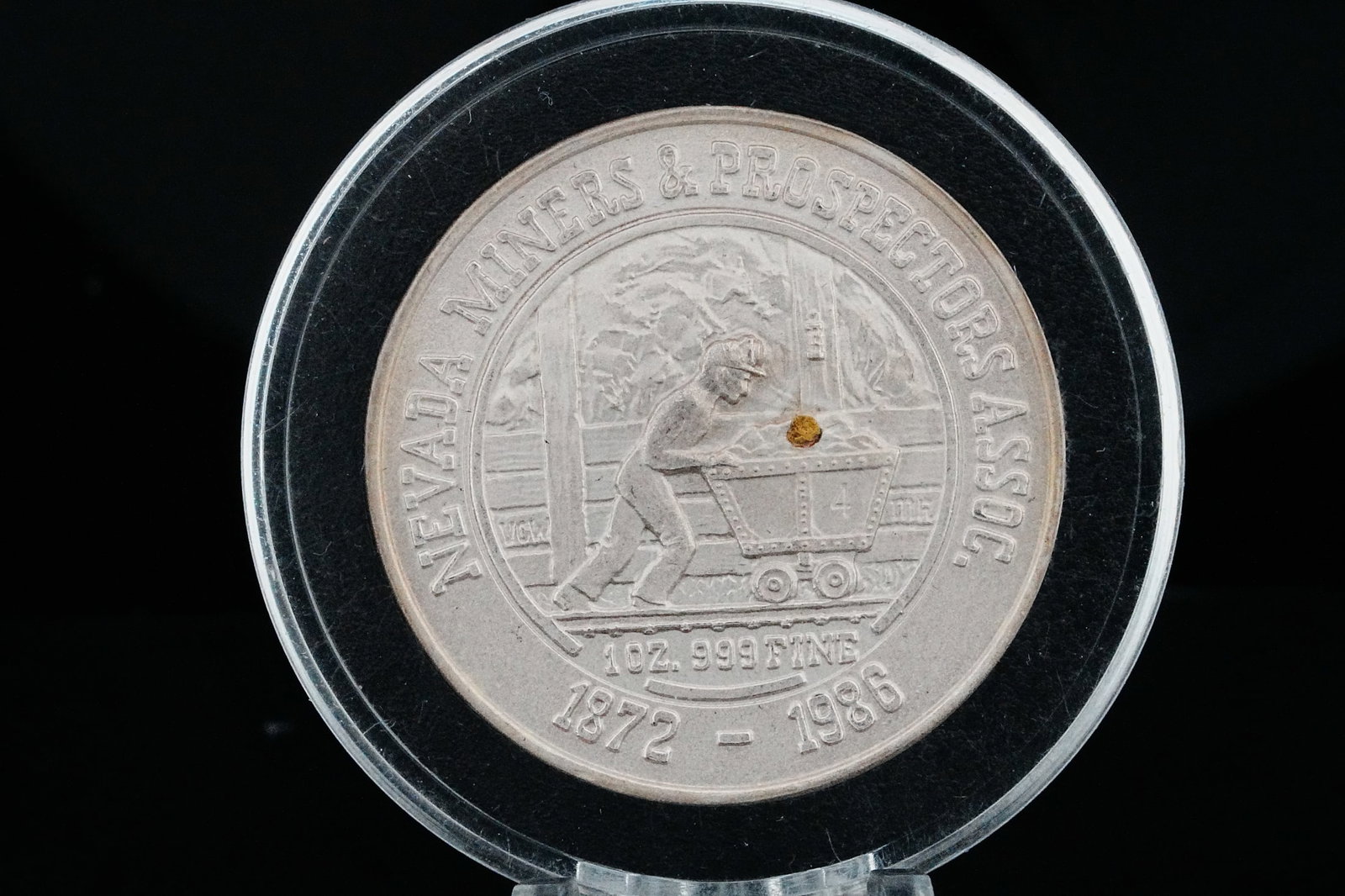 Nevada Miners 1 Ounce .999 Silver Gold Nugget Round: Nevada Miners and Prospectors Association 1 Ounce .999 Fine Silver Round with Gold Nugget - This collectible commemorative round is struck in 1 ounce of .999 fine silver and features detailed mining-t