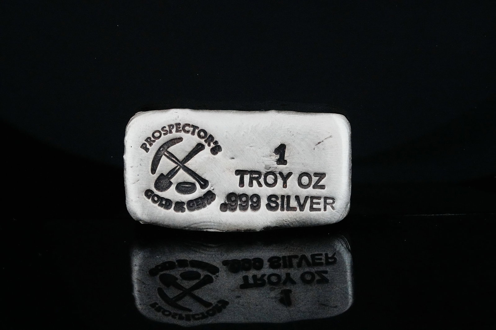1 Troy Ounce .999 Fine Silver Hand Poured Bullion Bar: 1 Troy Ounce .999 Fine Silver Prospector's Gold and Gems Hand Poured Bullion Bar - A distinctive artisan bullion piece, this 1 troy ounce .999 fine silver hand-poured bar was produced by Prospector's 