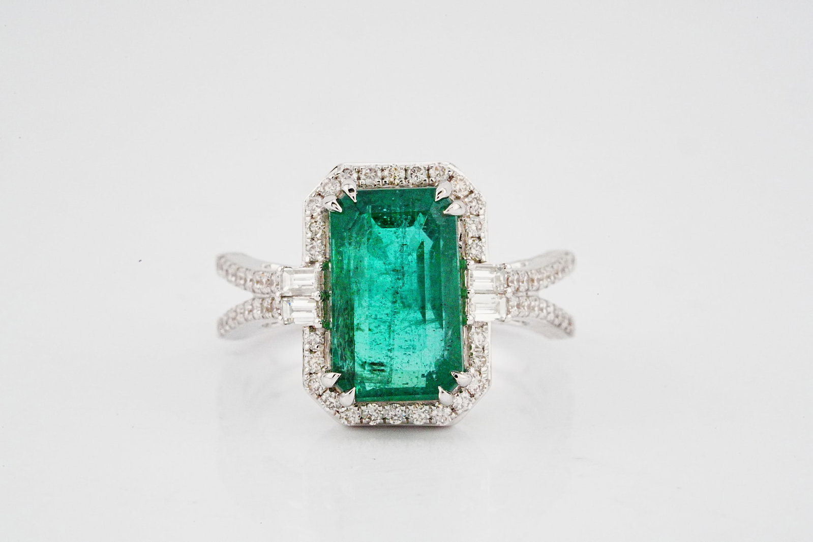 4.70ct Emerald, 0.65ctw Diamond and 18K White Gold Ring: 4.70ct Emerald, 0.65ctw Diamond and 18K White Gold Ring - THIS ITEM WILL COME WITH AN $11,500 INSURANCE VALUATION REPORT. A striking statement of elegance and sophistication, this exquisite ring is cr