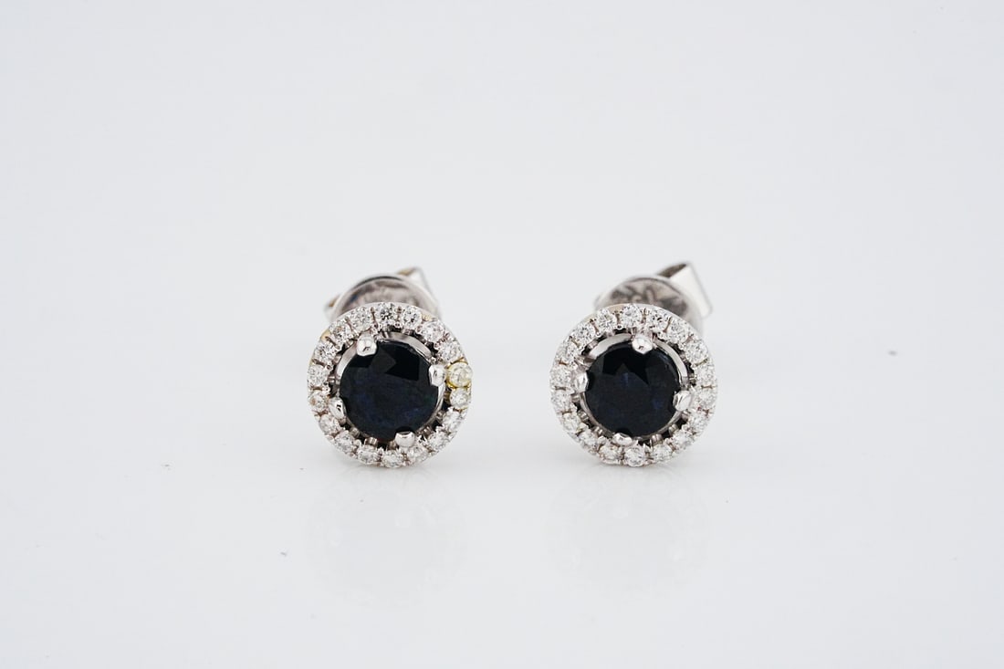 18K, 0.50ctw Sapphire and 0.15ctw Diamond Earrings: 18K White Gold, 0.50ctw Blue Sapphire and 0.15ctw Diamond Stud Earrings - These stud earrings are crafted in 18k white gold and feature approximately 0.50ctw blue sapphires surrounded by approximately