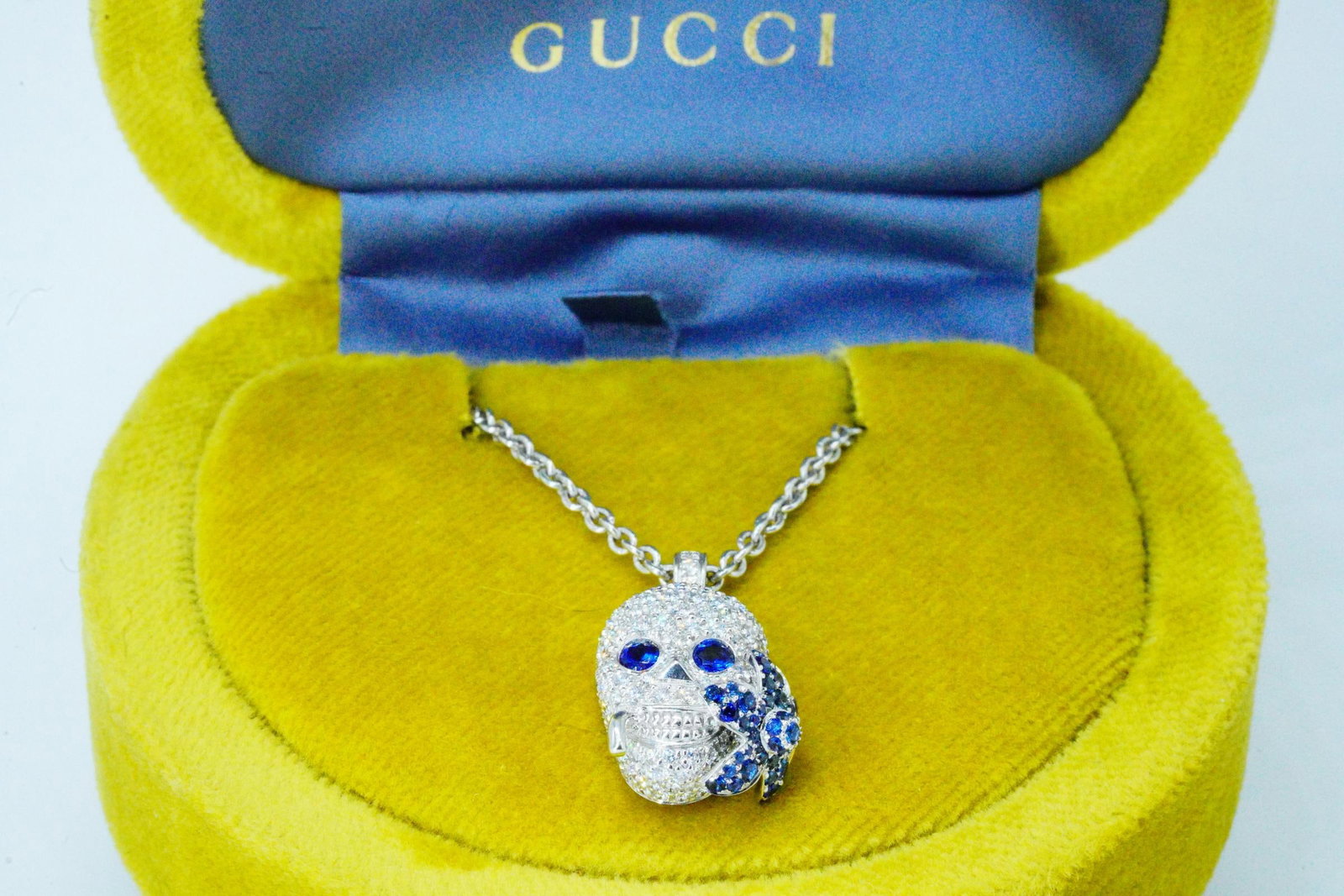 Gucci Flora 1.00ctw Diamond, Sapphire 18K Necklace: Gucci Flora 1.00ctw Diamond and Blue Sapphire and 18K White Gold 23" Skull Pendant Necklace W/Box - This lovely piece from Gucci's Flora collection features a meticulously crafted skull pendant hangin