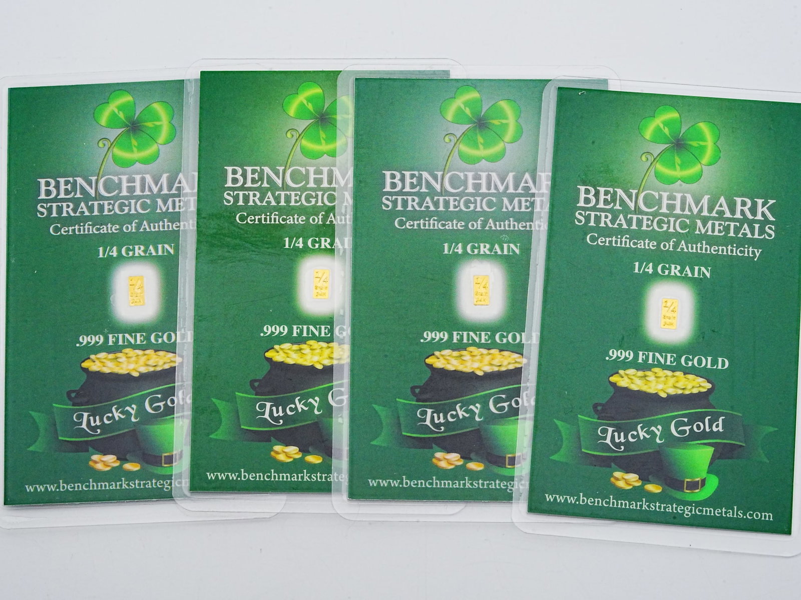 Lot of (4) 1/4 Grain .999 Fine Gold "Lucky Gold" Bars: Lot of (4) Benchmark Strategic Metals 1/4 Grain .999 Fine Gold "Lucky Gold" Bars in Sealed Certificates - A collectible and novelty fractional gold lot featuring four Benchmark Strategic Metals "Lucky