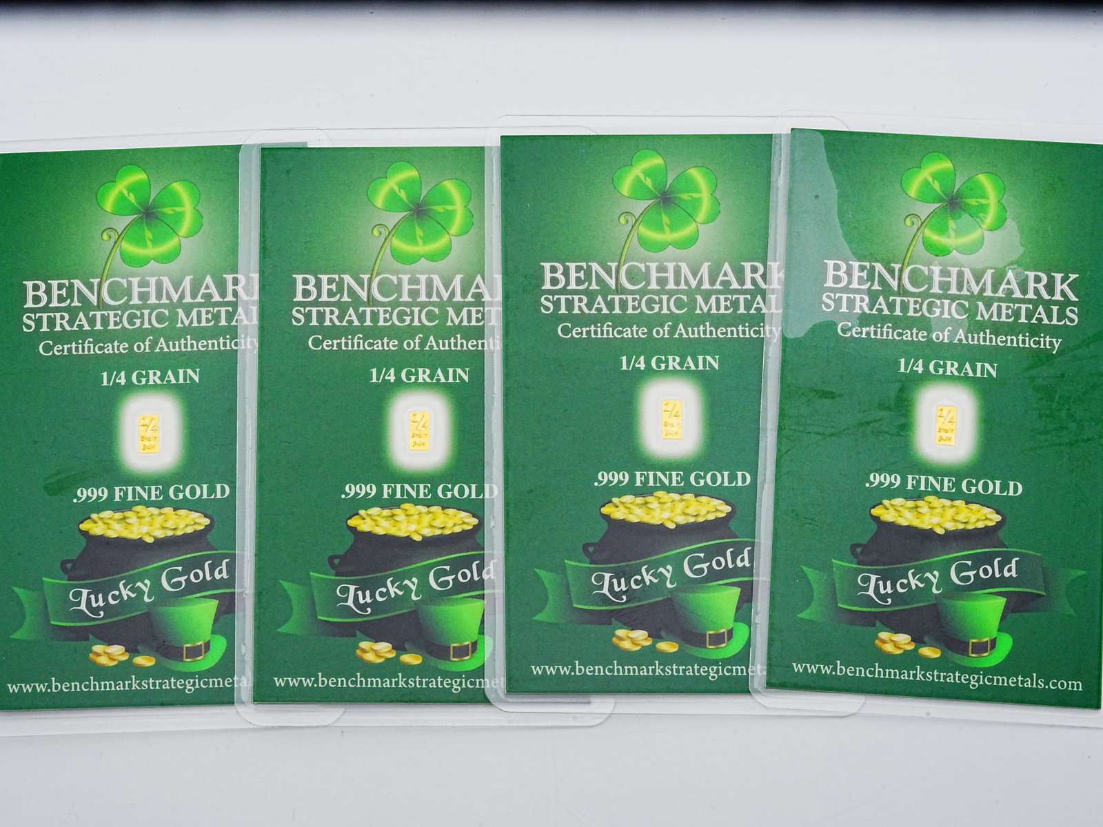 Lot of (4) 1/4 Grain .999 Fine Gold "Lucky Gold" Bars: Lot of (4) Benchmark Strategic Metals 1/4 Grain .999 Fine Gold "Lucky Gold" Bars in Sealed Certificates - A collectible and novelty fractional gold lot featuring four Benchmark Strategic Metals "Lucky