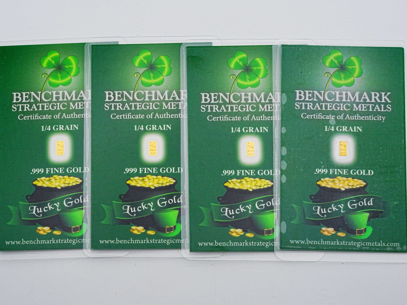 Lot of (4) 1/4 Grain .999 Fine Gold "Lucky Gold" Bars: Lot of (4) Benchmark Strategic Metals 1/4 Grain .999 Fine Gold "Lucky Gold" Bars in Sealed Certificates - A collectible and novelty fractional gold lot featuring four Benchmark Strategic Metals "Lucky
