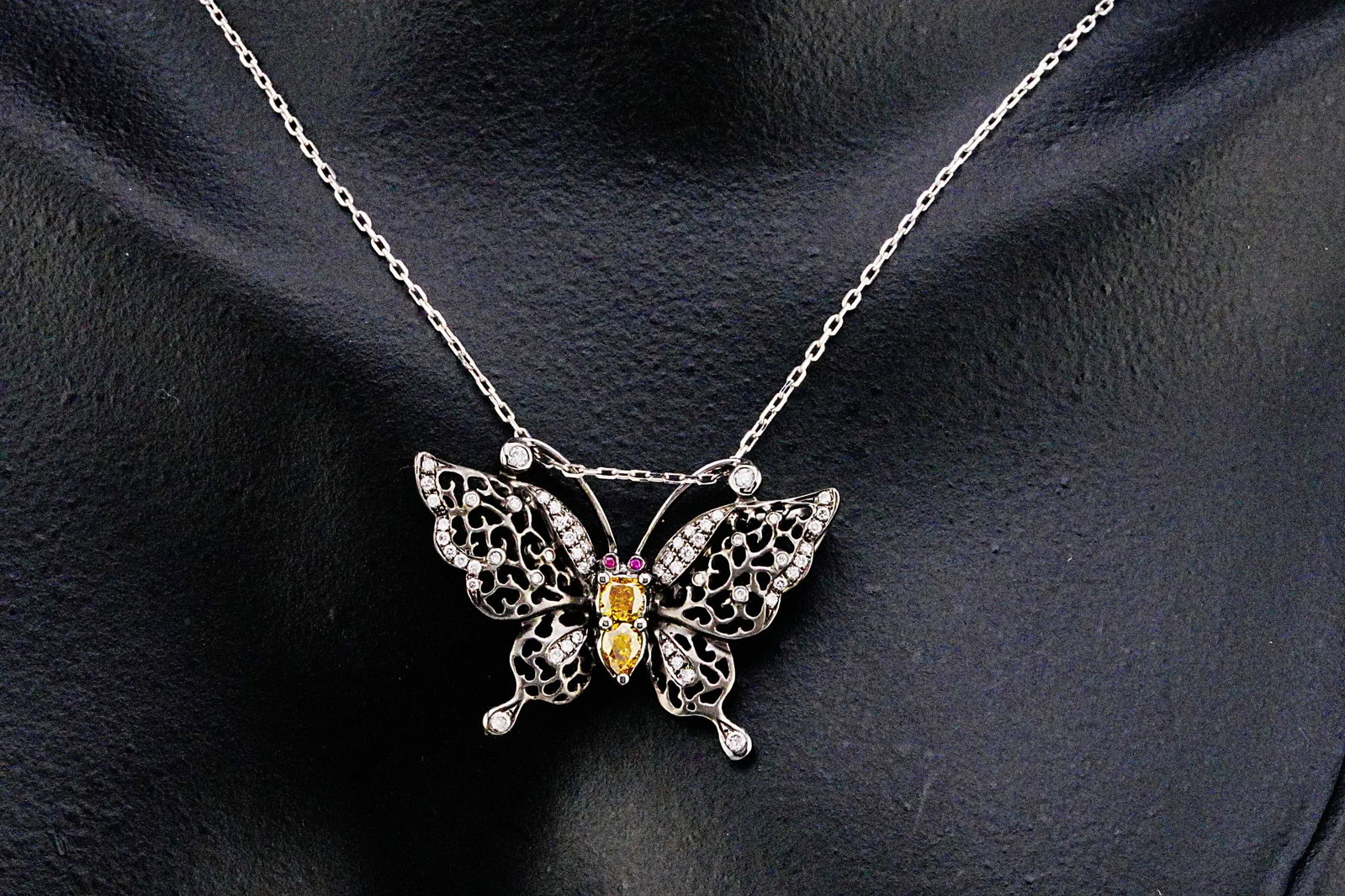 14K, 0.60ctw Diamond, and Ruby 18" Butterfly Necklace: 14K White Gold, 0.60ctw Yellow and White Diamond, Ruby Accented 18" Butterfly Pendant Necklace - THIS ITEM WILL COME WITH A $6,000 INSURANCE VALUATION REPORT. An elegant and whimsically sophisticated 