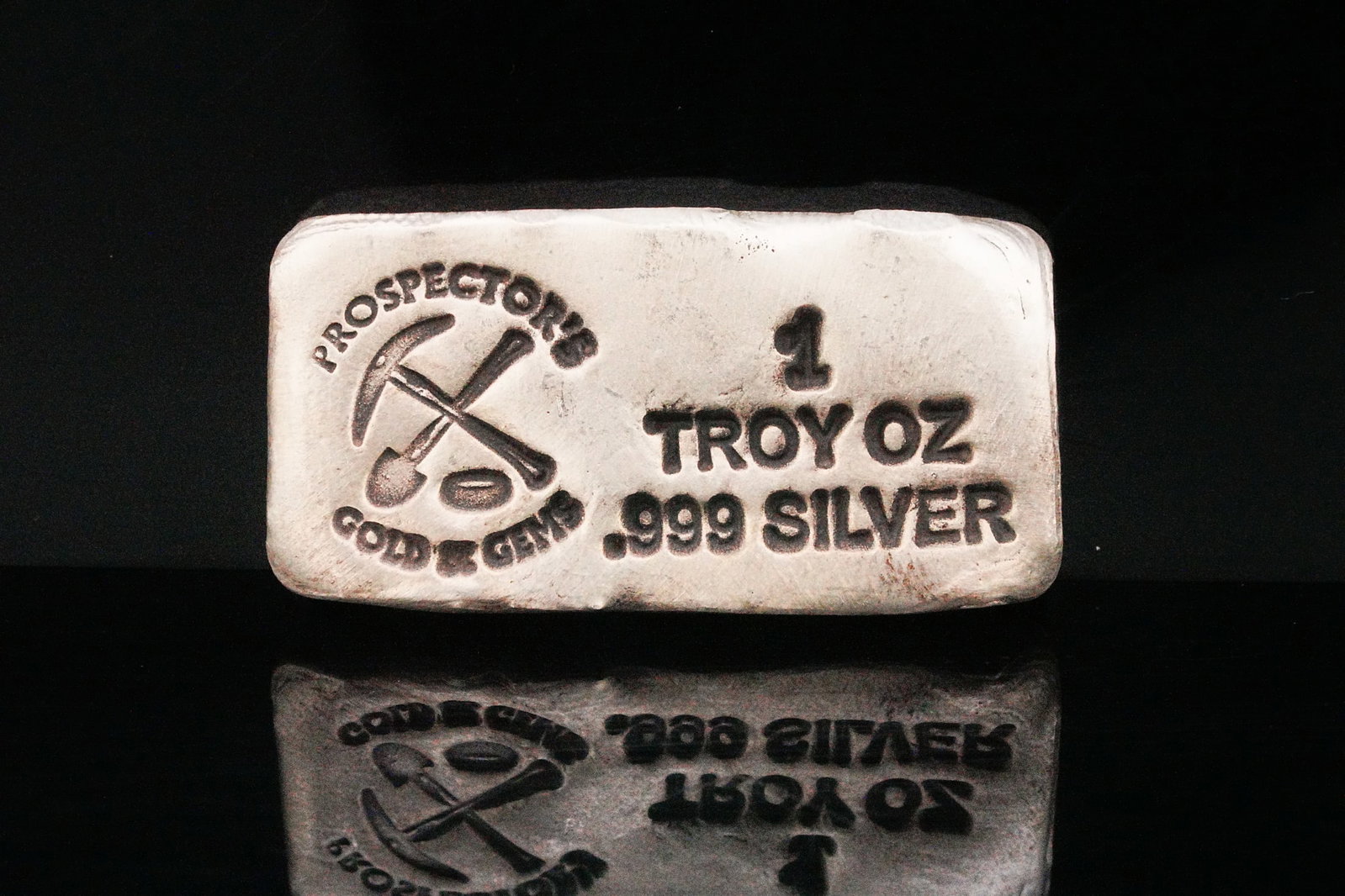 Prospector's Gold and Gems 1 Troy Oz .999 Silver Bar: Prospector's Gold and Gems 1 Troy Ounce .999 Fine Silver Hand Poured Bullion Bar - A distinctive artisan bullion piece, this 1 troy ounce .999 fine silver hand-poured bar was produced by Prospector's 