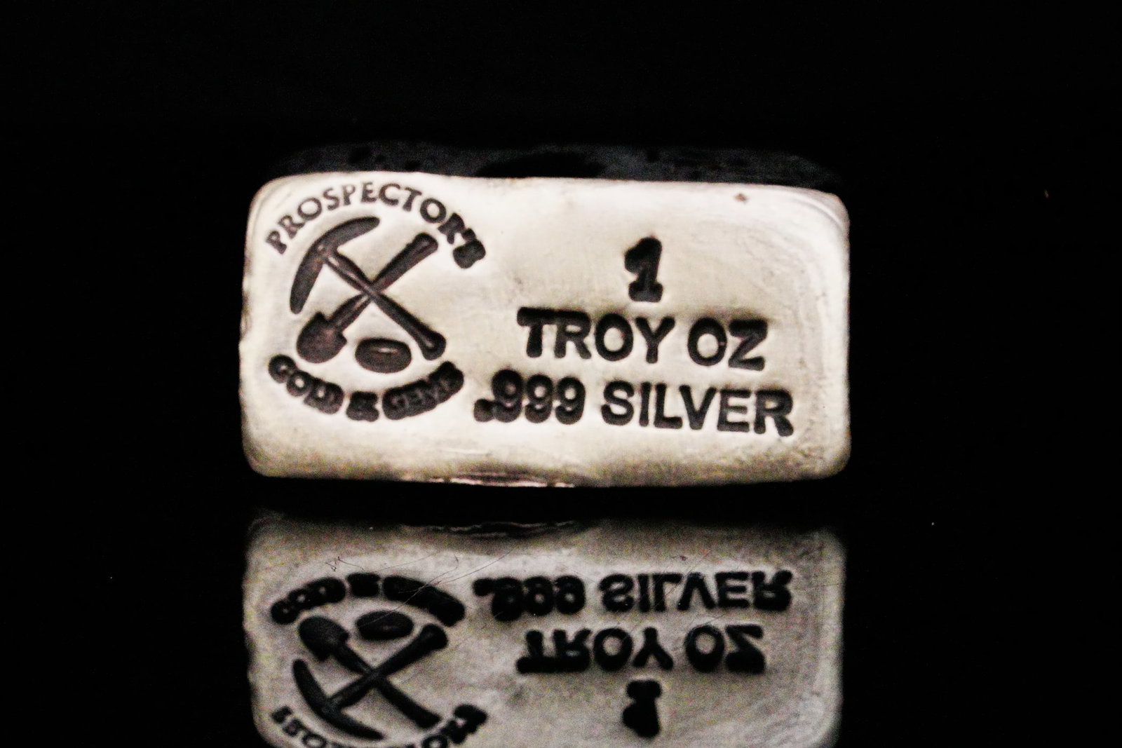 Prospector's Gold and Gems 1 Troy Oz .999 Silver Bar: Prospector's Gold and Gems 1 Troy Ounce .999 Fine Silver Hand Poured Bullion Bar - A distinctive artisan bullion piece, this 1 troy ounce .999 fine silver hand-poured bar was produced by Prospector's 