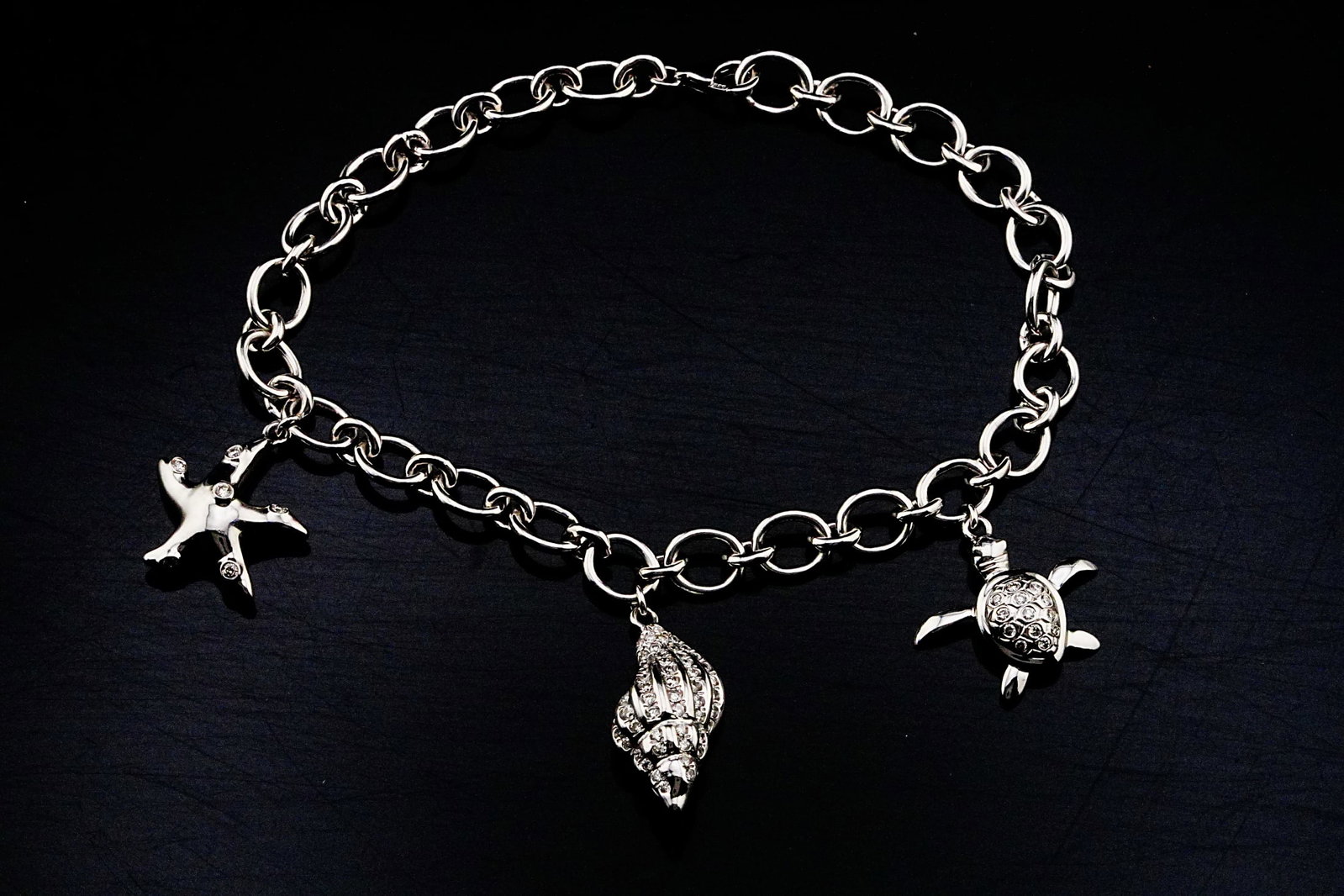 14K White Gold and 0.60ctw Diamond 7" Charm Bracelet: 14K White Gold and 0.60ctw Diamond 7" Sea Life Charm Bracelet - THIS ITEM WILL COME WITH A $9,000 INSURANCE VALUATION REPORT. An enchanting expression of coastal elegance, this exceptional bracelet is
