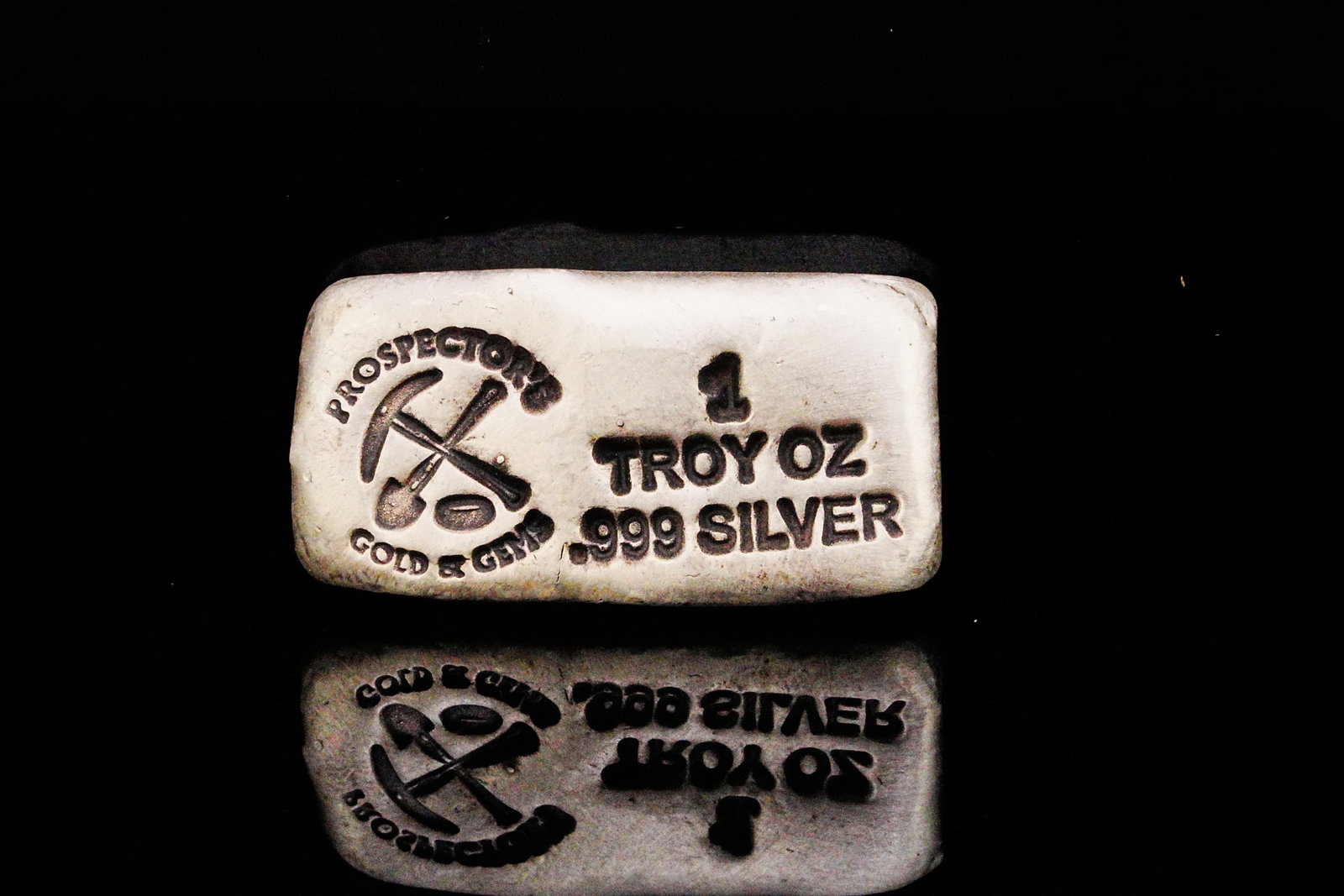 Prospector's Gold and Gems 1 Troy Oz .999 Silver Bar: Prospector's Gold and Gems 1 Troy Ounce .999 Fine Silver Hand Poured Bullion Bar - A distinctive artisan bullion piece, this 1 troy ounce .999 fine silver hand-poured bar was produced by Prospector's 
