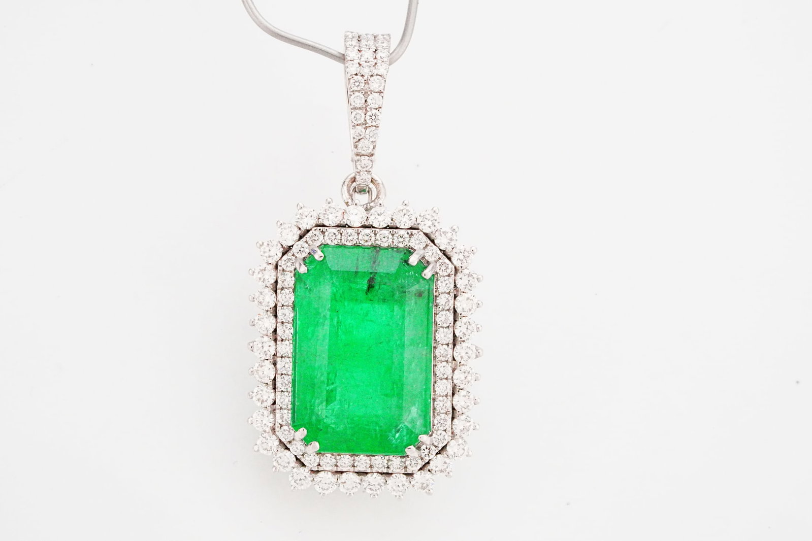 9.85ct Emerald, 1.35ctw Diamond and 18K 1.5" Pendant: 9.85ct Emerald, 1.35ctw VS2-SI1/G-H Diamond and 18K White Gold 1.5" Pendant - THIS ITEM WILL COME WITH A $15,500 INSURANCE VALUATION REPORT. Rich in color and timeless in design, this exceptional pend