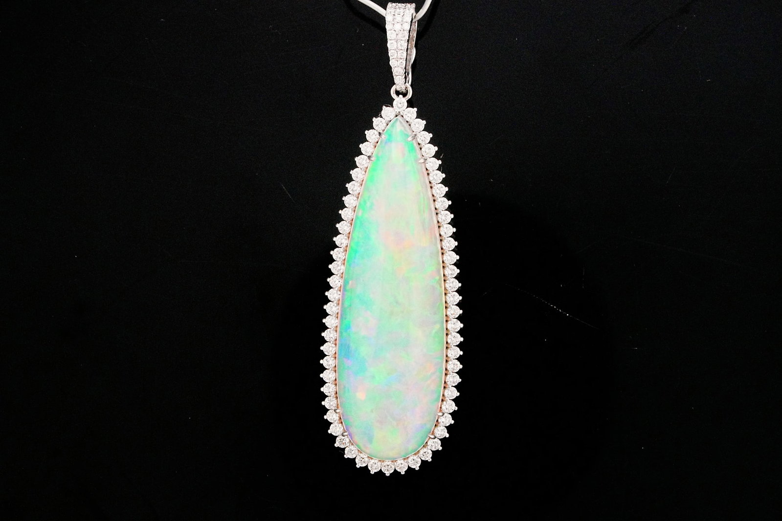 34.05ct Opal, 1.60ctw Diamond and 18K 2.60" Pendant: 34.05ct Opal, 1.60ctw VS1-SI1/G-H Diamond and 18K White Gold 2.60" Pendant - THIS ITEM WILL COME WITH A $15,000 INSURANCE VALUATION REPORT. A truly extraordinary statement jewel, this exceptional pend