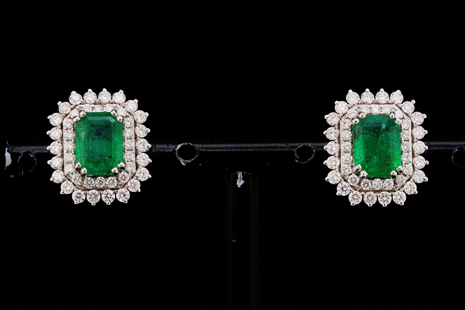 3.05ctw Emerald, 1.15ctw Diamond and 18K Earrings: 3.05ctw Emerald, 1.15ctw VS1-VS2/G-H Diamond and 18K White Gold 0.60" Double Halo Stud Earrings - THIS ITEM WILL COME WITH A $12,000 INSURANCE VALUATION REPORT. Showcasing approximately 3.05 carats to