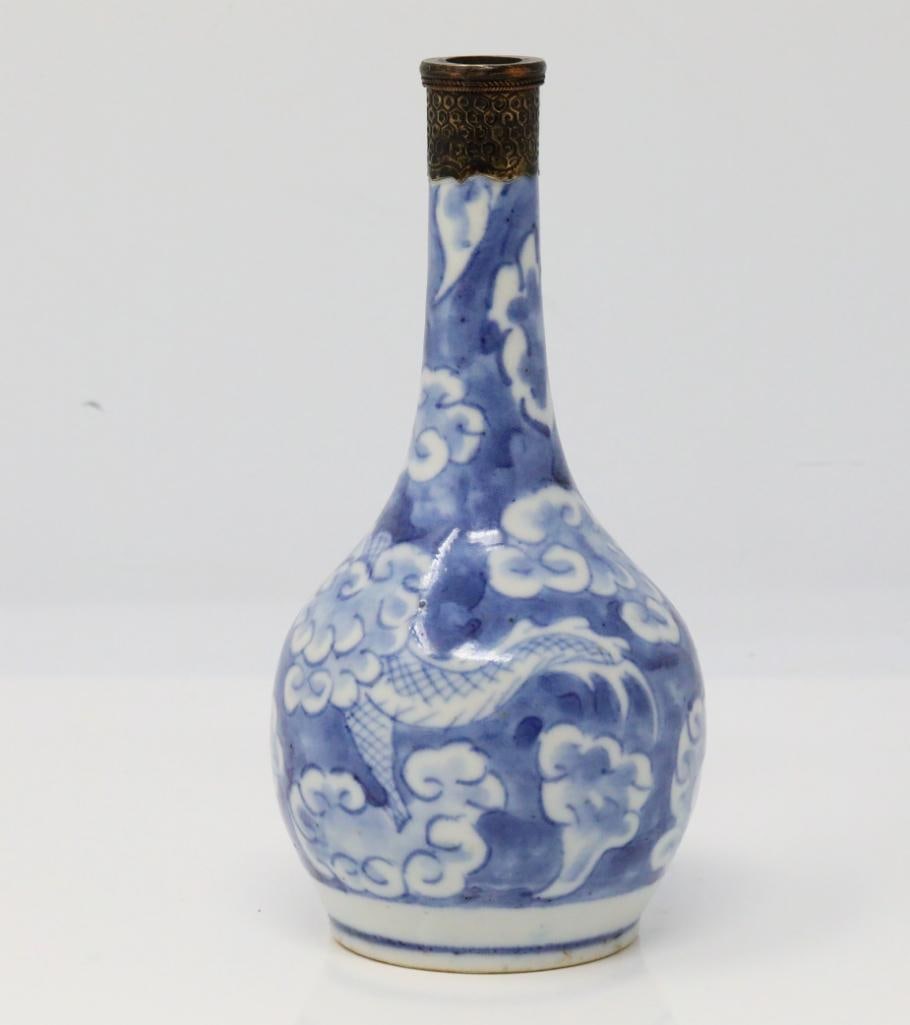 Vietnamese Blue and White Porcelain Vase: Vietnamese Blue and White Porcelain Vase W/Dragon Motif and Metal Top - This porcelain vase is decorated with a scrolling dragon amongst a densely populated background of stylized clouds. The vase is 