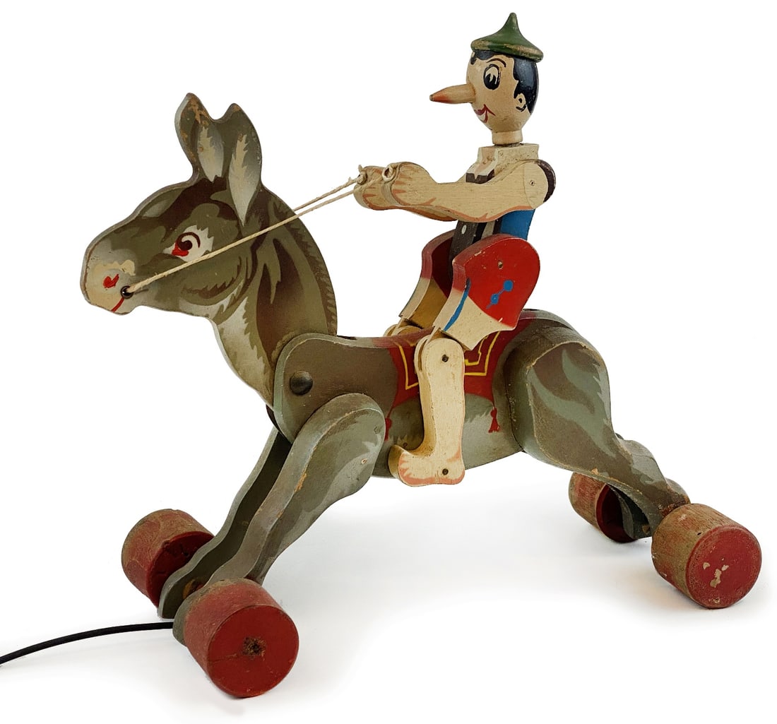 Pinocchio e il Ciuchino: Gioco da trascinamento in legno sagomato con arti snodabili, made in Italy, anni '40. Cm 27x19. Buono stato.