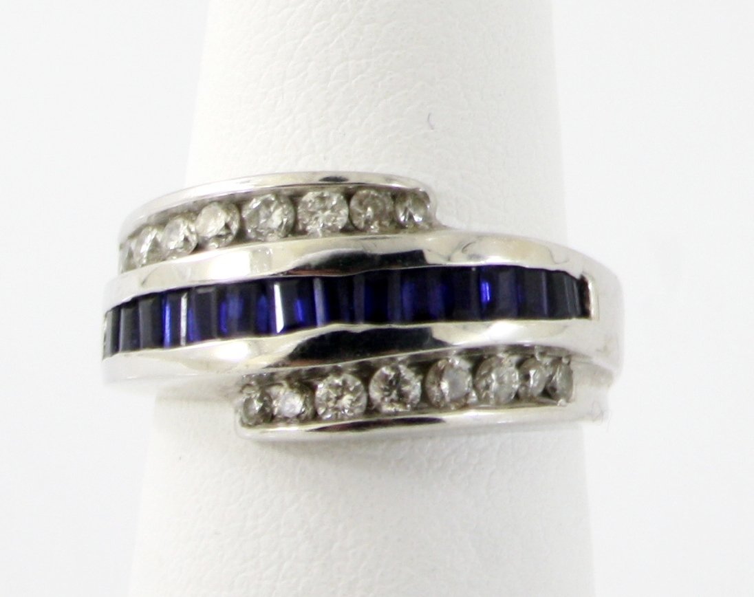 14KT WHITE GOLD SAPPHIRE AND WHITE DIAMOND RING: A very fine 14kt solid gold .585 purity NATURAL BLUE SAPPHIRE AND WHITE DIAMOND RING. This ring features 16 blue sapphire channel setting in the middle and white diamond on each side. This ring is ele