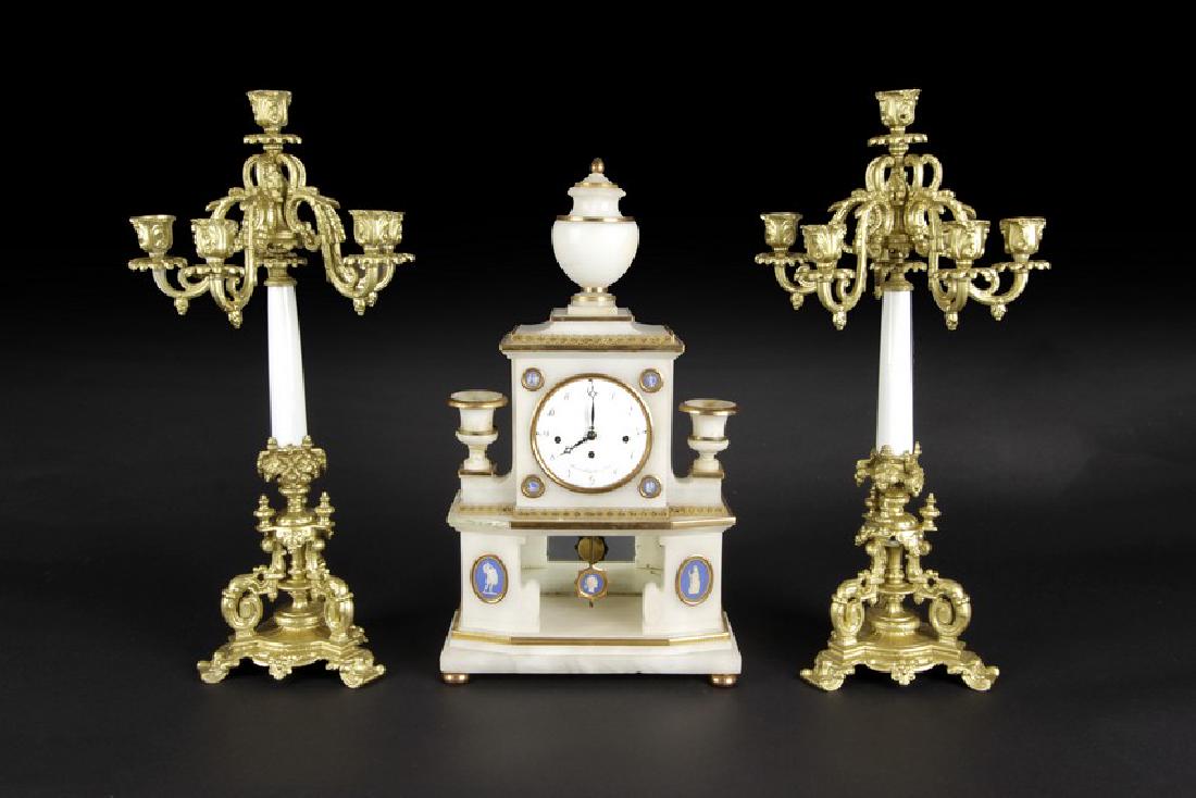A SET OF FRENCH WHITE MARBLE AND GILT BRONZE GARNITURE: Comprising a pair of en-suite five-stick candelabra, the clock shaped similar to clock tower, with two candle holders on the side. Height: 22 1/8 in (56.3 cm) Width: 7 in (17.8 cm)